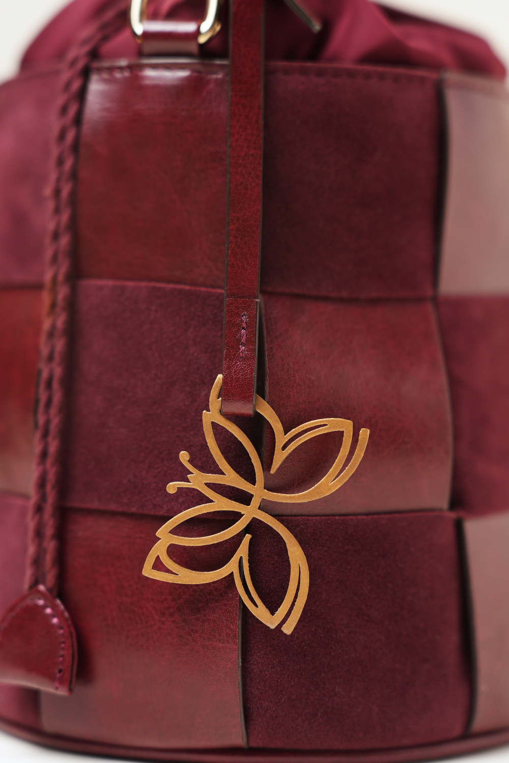 Close-up of the Derby Bucket Bag Burgundy showing the Amrée logo, fine stitching, and textured finish.
