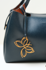 Close-up of the Equitana Top Handle Navy handbag showing the Amrée logo detailing on the front.