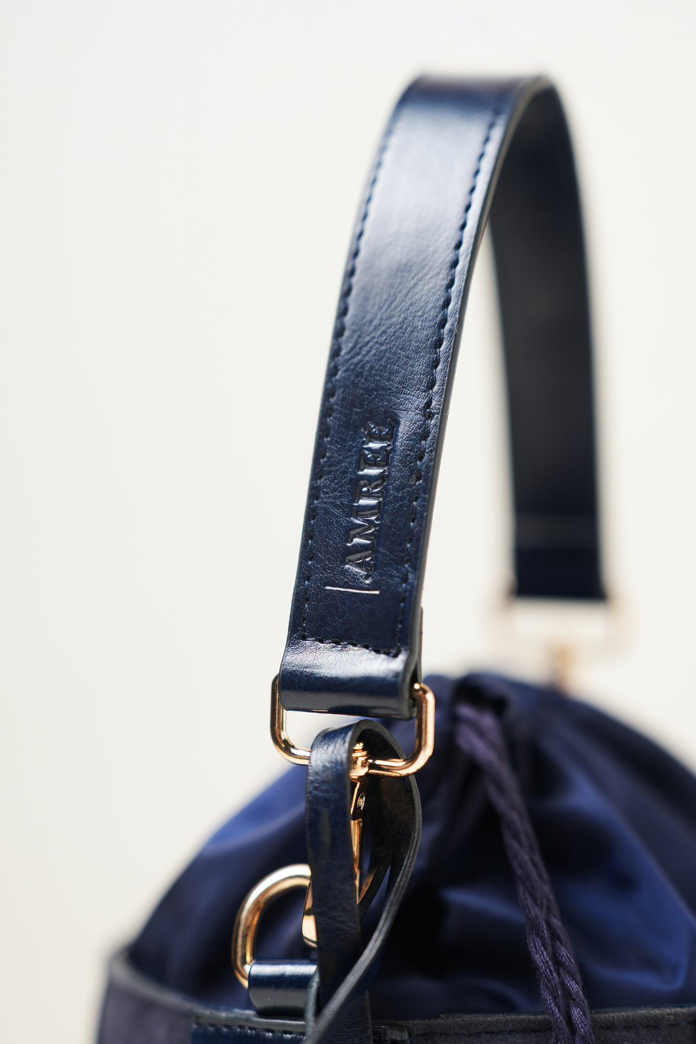 Close-up of the Derby Bucket Bag Blue showing the Amrée brand tag on the strap with clean stitching and premium detailing.
