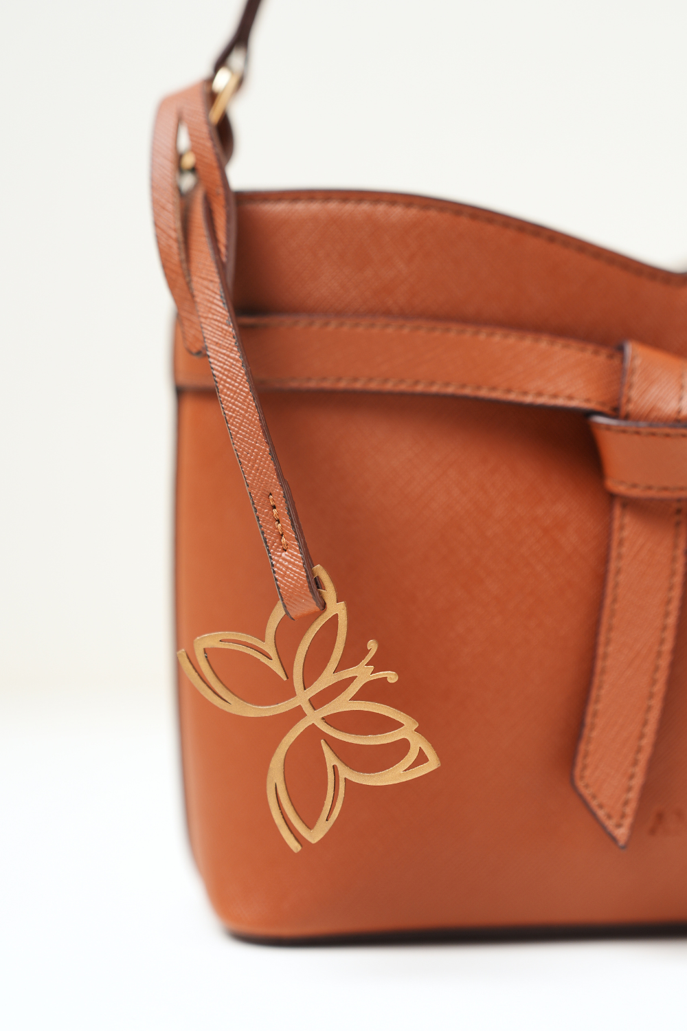 Close-up of the Rosette Sling Tan showing the Amrée logo detailing and fine stitching.