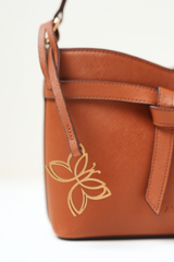 Close-up of the Rosette Sling Tan showing the Amrée logo detailing and fine stitching.