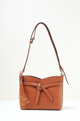 Rosette Sling Tan shown in a full front view highlighting its compact silhouette and warm tan finish.